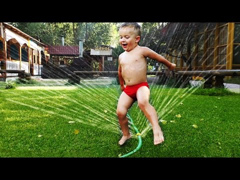 Roma-i-detki-prikolno-razvlekayutsya-na-gazone-s-fontanom-dlya-poliva.-Kak-veselo-ohlazhdatsya-letom